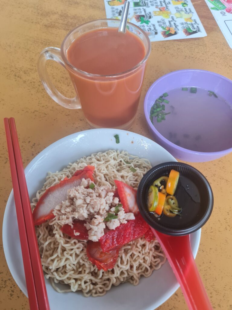 A bowl of authentic Sarawak Kolo Mee with char siew and minced meat served with Teh C Special.
