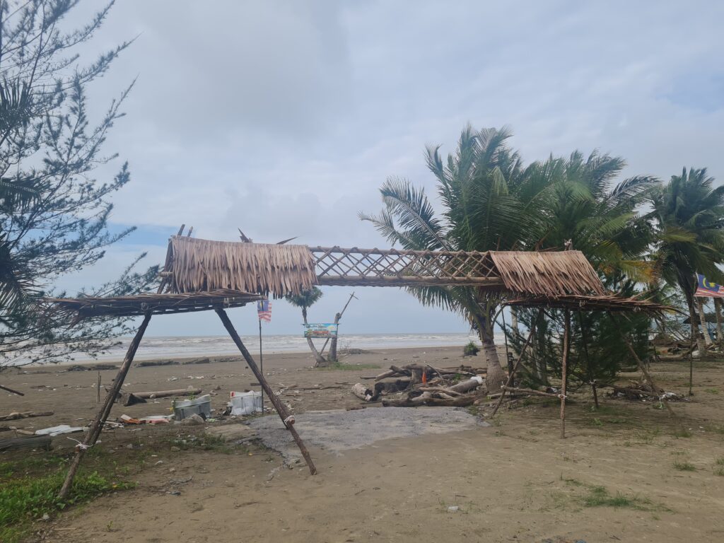 Traditional bamboo archway entrance at Redbee Camp flying the Sarawak state flag.