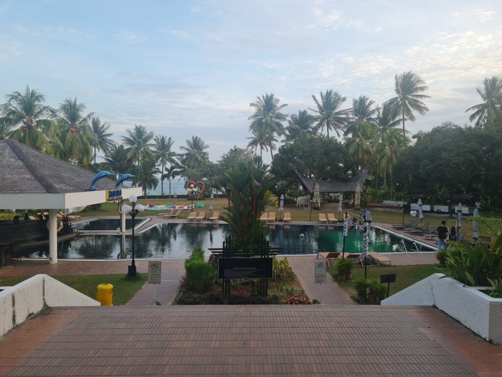 Large outdoor swimming pool with dolphin statues and palm trees at Batam View Beach Resort.
