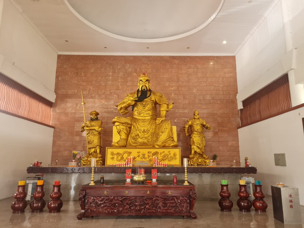 Powerful golden statue of General Guan Yu flanked by attendants at the Batam temple.