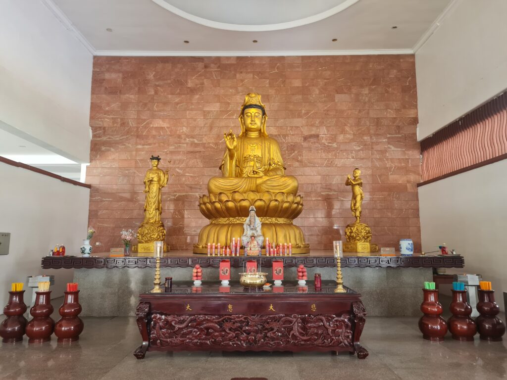 Golden statue of Guanyin Bodhisattva on a red marble altar inside the monastery.