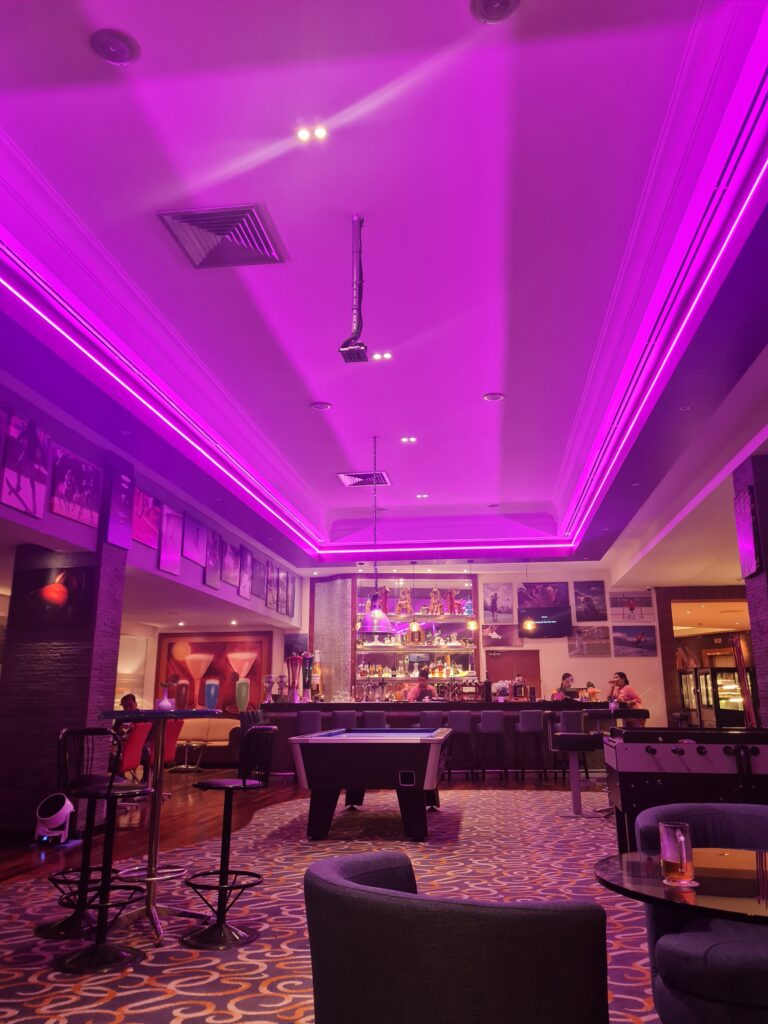 Interior of the Islander Lobby Lounge bar with purple lighting and pool table.
