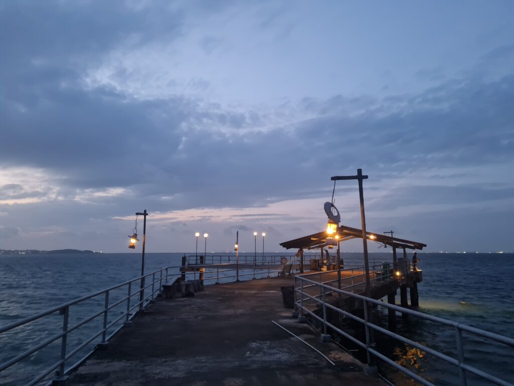 Wooden jetty entrance to Kelong Seafood Sunset Bistro at Batam View Beach Resort during golden hour.