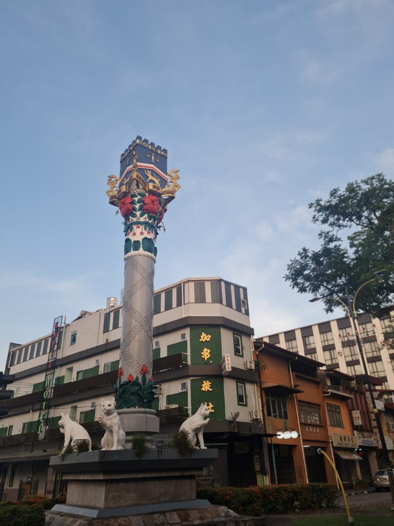 The iconic white cat statue monument in Kuching city center against a clear morning sky.