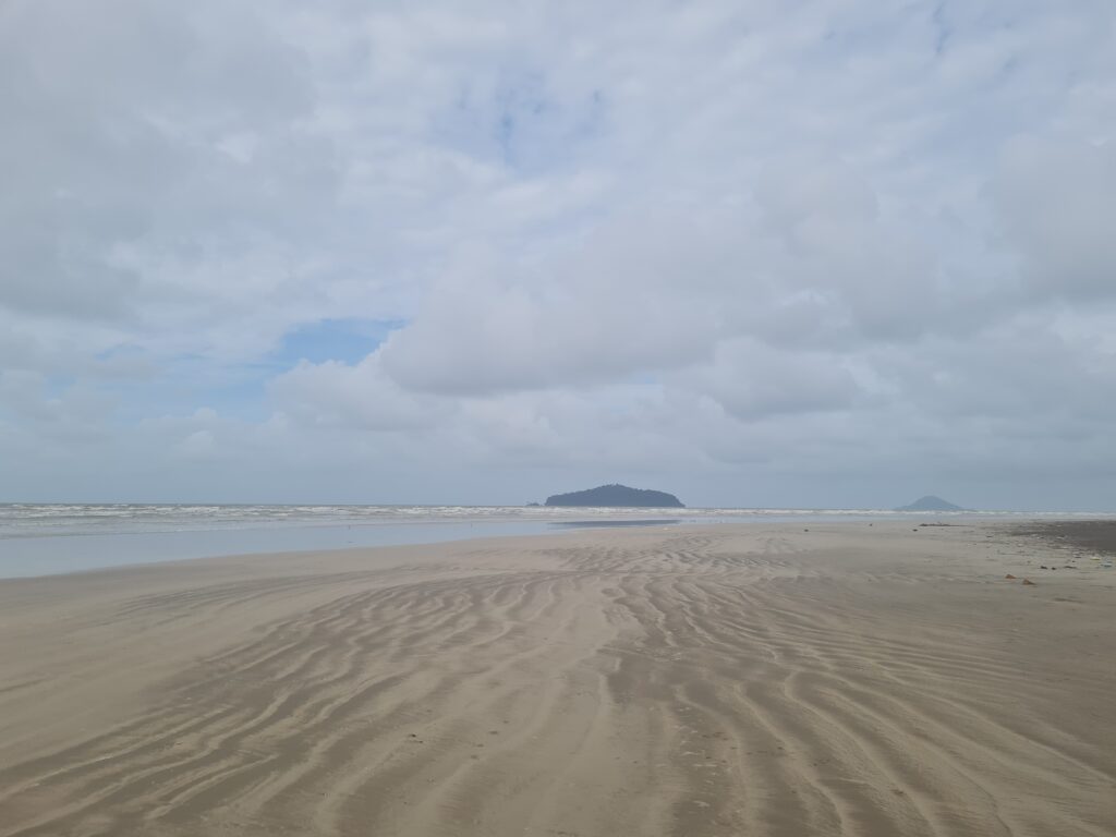 Wide angle view of the beach at Redbee Camp with Talang-Talang Island visible on the horizon.