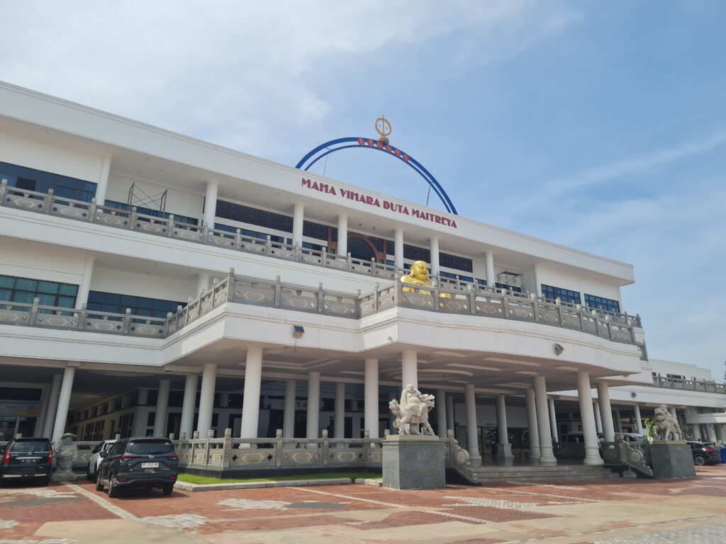 Wide shot of the white exterior and entrance of Maha Vihara Duta Maitreya Monastery in Batam.