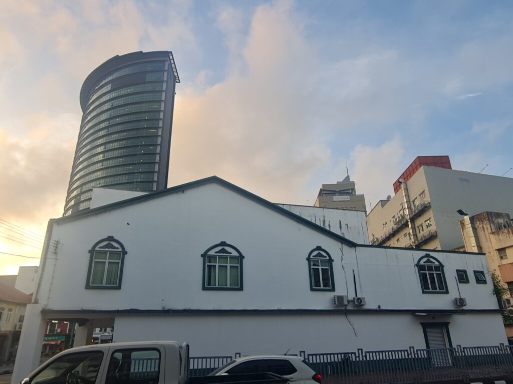 Modern high-rise building juxtaposed with heritage architecture in Kuching, Sarawak.