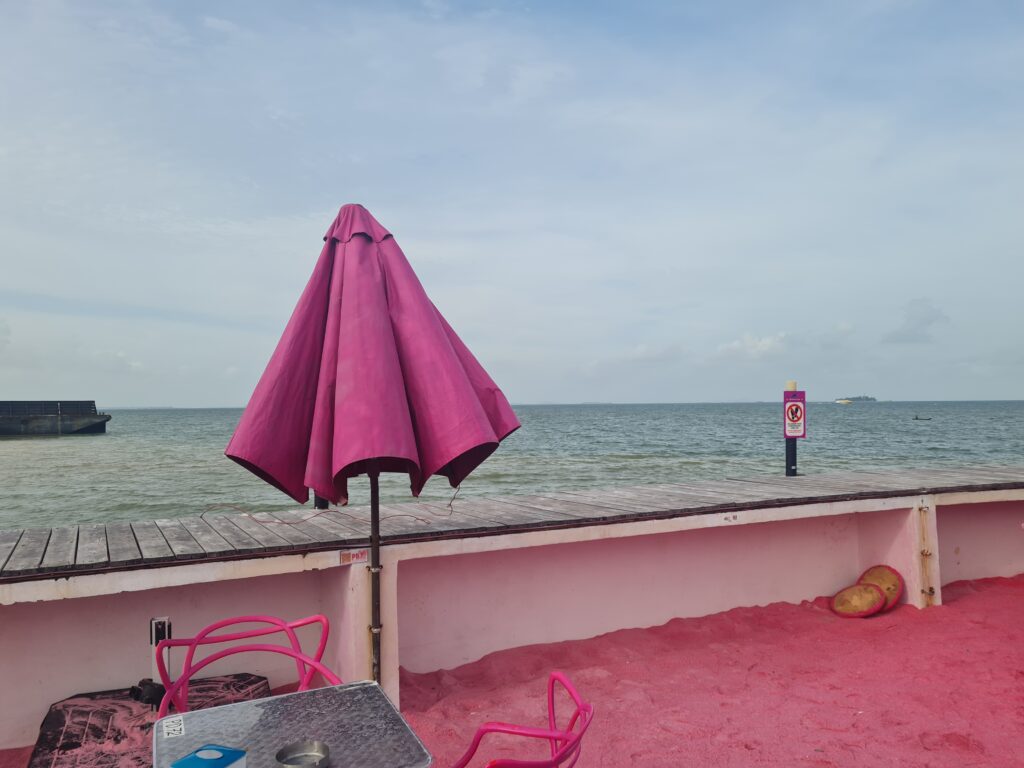 Pink pastel beach umbrellas providing shade over the seating area with ocean view at the club