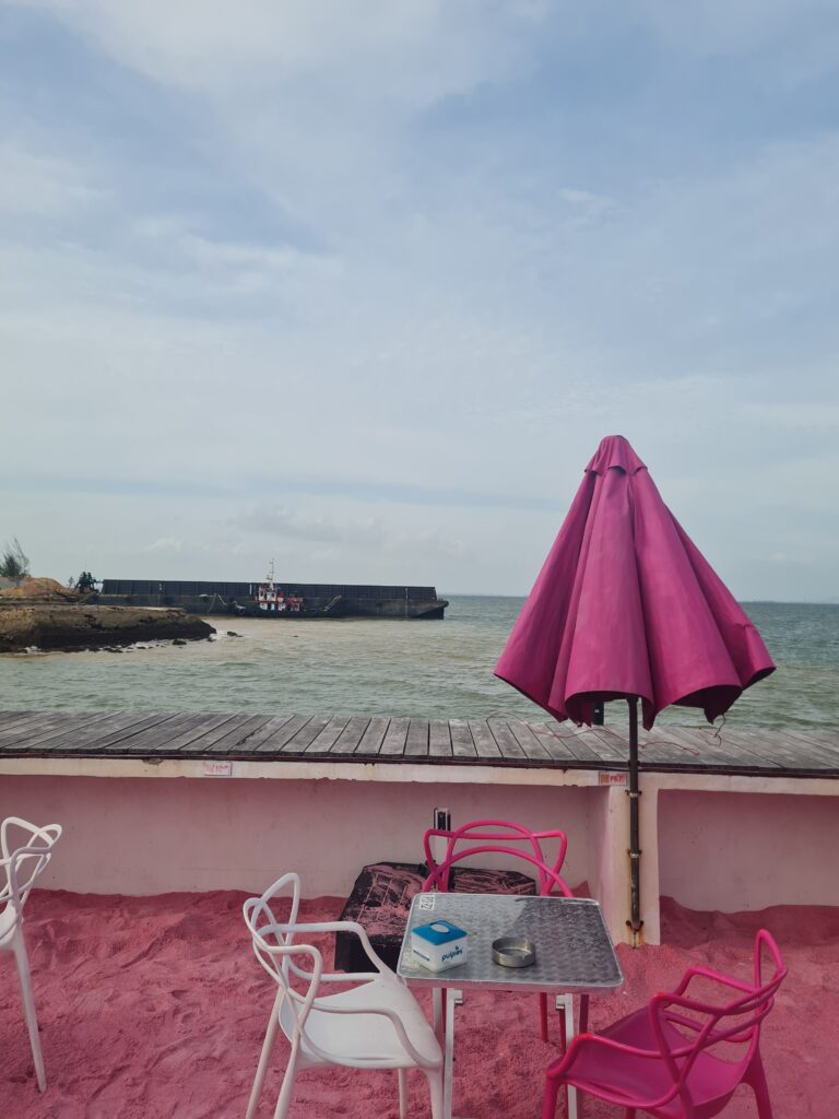 Pink pastel beach umbrellas providing shade over the seating area at the club.