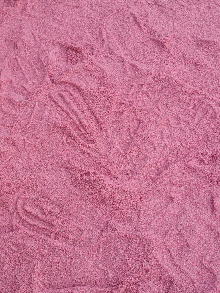 Close-up detail of the pink-painted sand texture at Bluefire Beach Club.