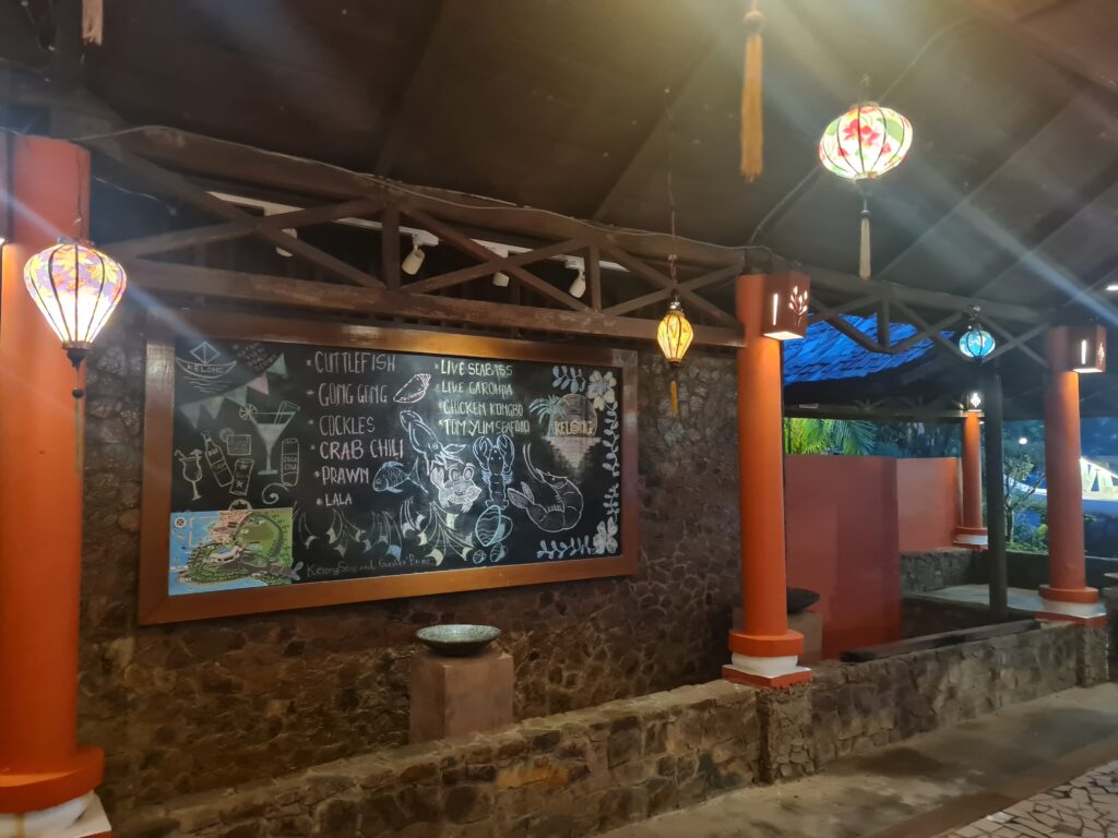 Menu board at Kelong Seafood Sunset Bistro showing prices for Gong Gong, Crabs, and live seafood.