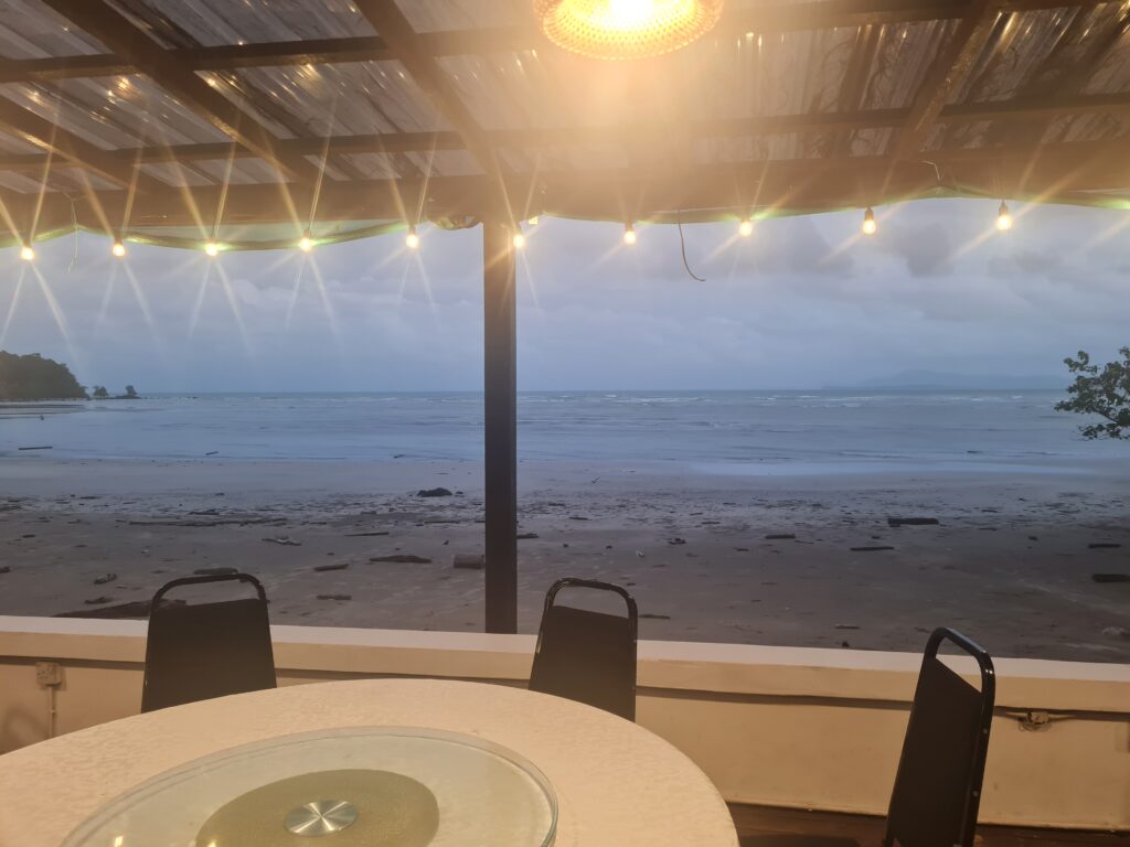 View of the ocean from a seaside restaurant in Lundu with warm ambient lighting.
