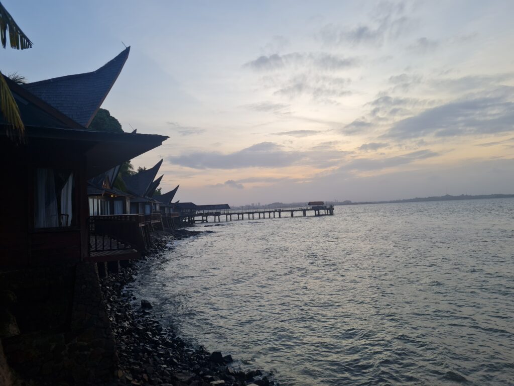 Seafront villas perched on the rocky coast at Batam View Beach Resort during sunset.